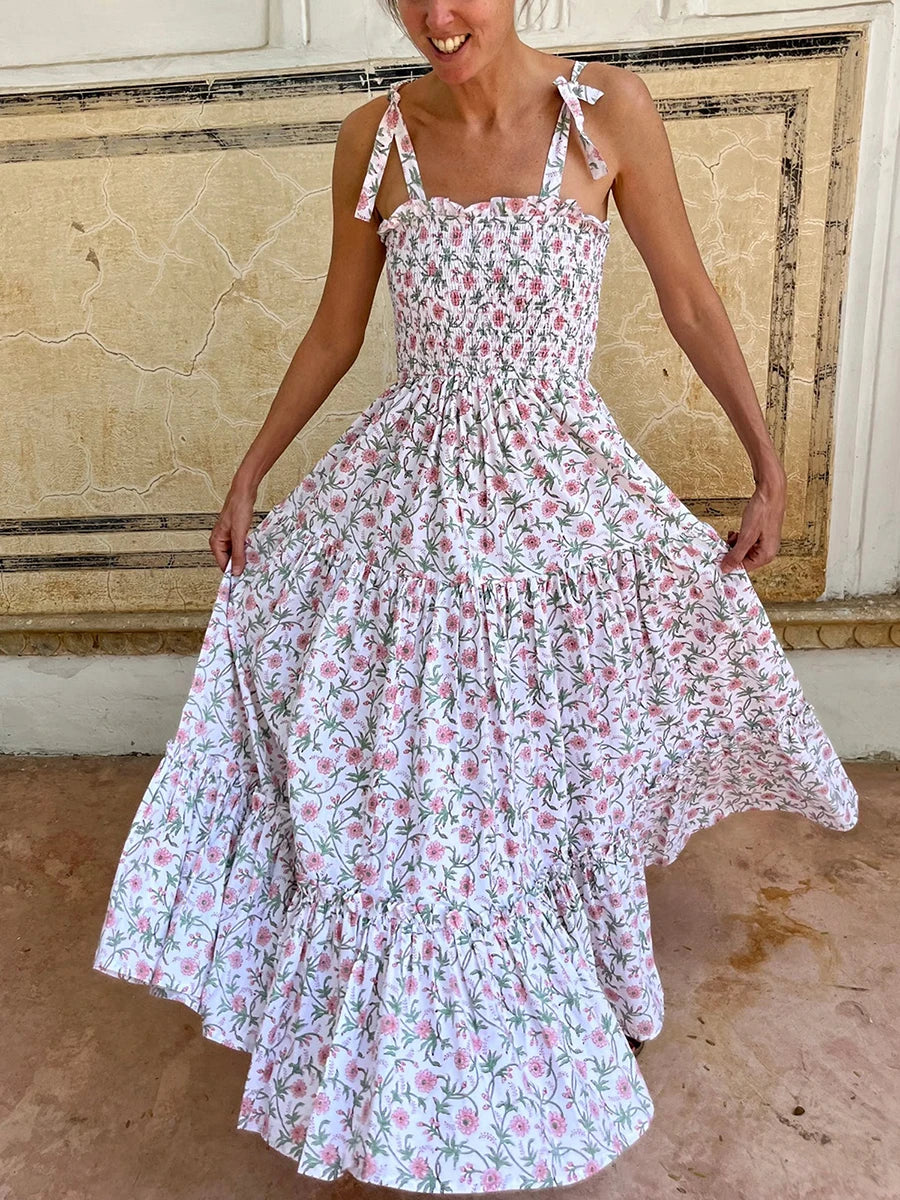 Woman wearing a floral dress standing in front of a textured wall.