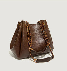 Brown leather handbag with chain detail on a light gray background
