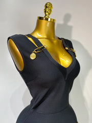 Black dress on a mannequin with gold accents against a white background
