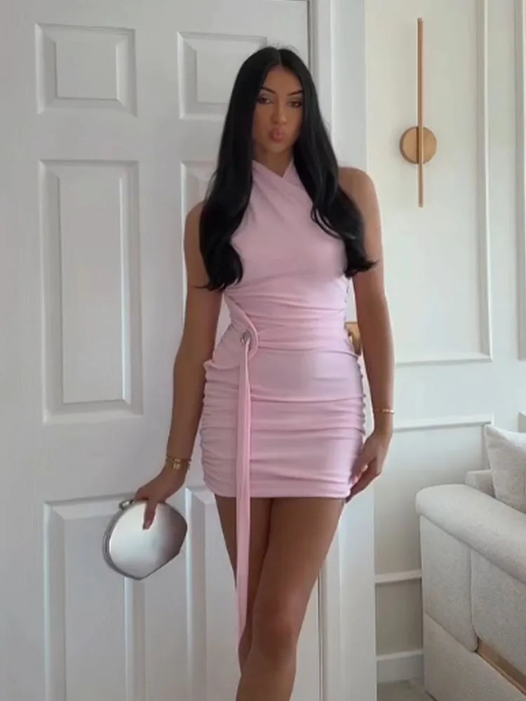 Woman wearing a pink dress standing in a room with white walls and a couch.