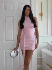 Woman wearing a pink dress standing in a room with white walls and a couch.