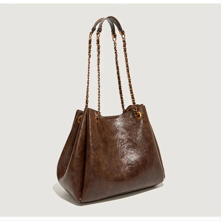 Brown leather handbag with braided handle on a light gray background