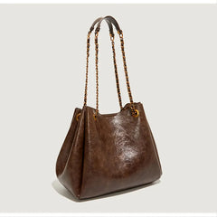 Brown leather handbag with braided handle on a light gray background