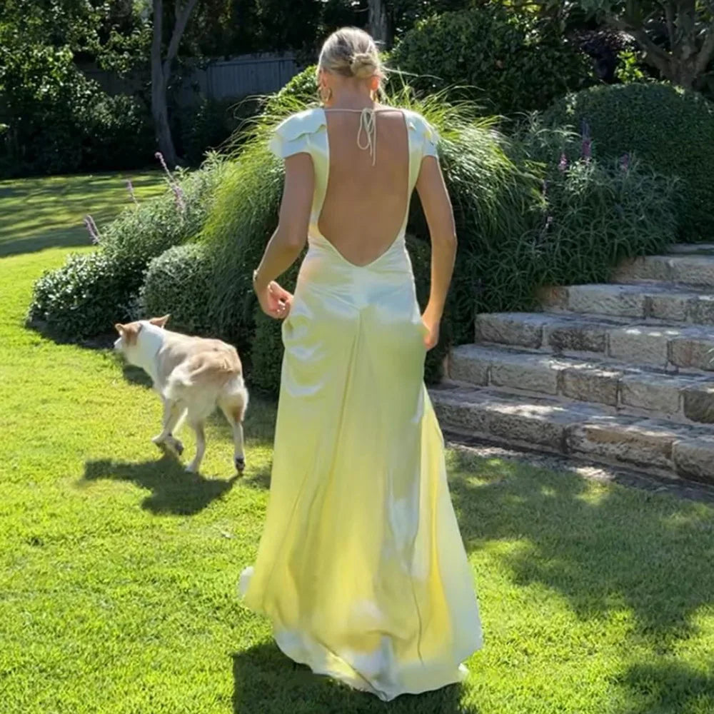 Woman in a yellow dress walking a dog in a garden