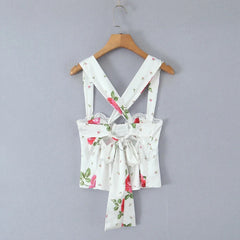 Floral-patterned dress with suspenders on a wooden hanger against a gray background