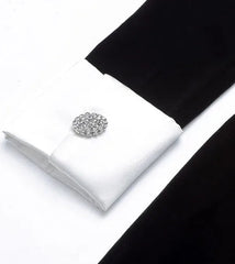 Silver cufflinks on a white box with black fabric in the background