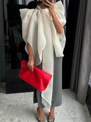 Oversized bow neck cape top held with red clutch