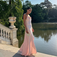 Woman in a pink dress standing by a pond with trees in the background
