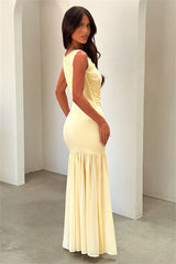 Woman wearing a yellow dress standing against a white wall.