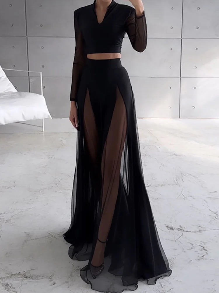 Person wearing a black outfit with sheer panels in a minimalistic setting