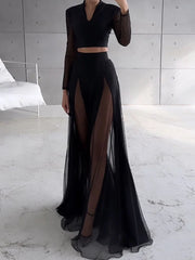 Person wearing a black outfit with sheer panels in a minimalistic setting