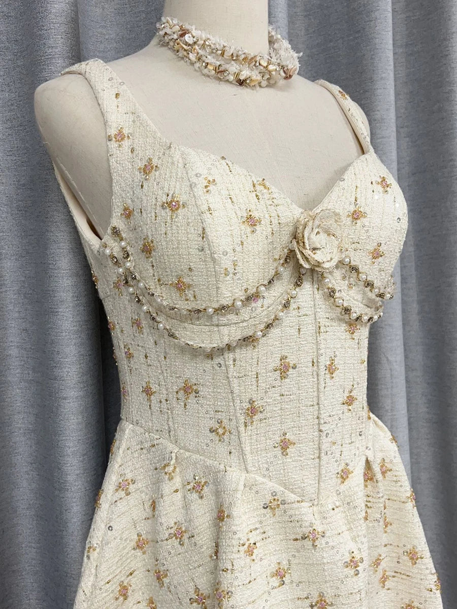 Mannequin wearing a cream-colored dress with floral embellishments against a gray curtain background