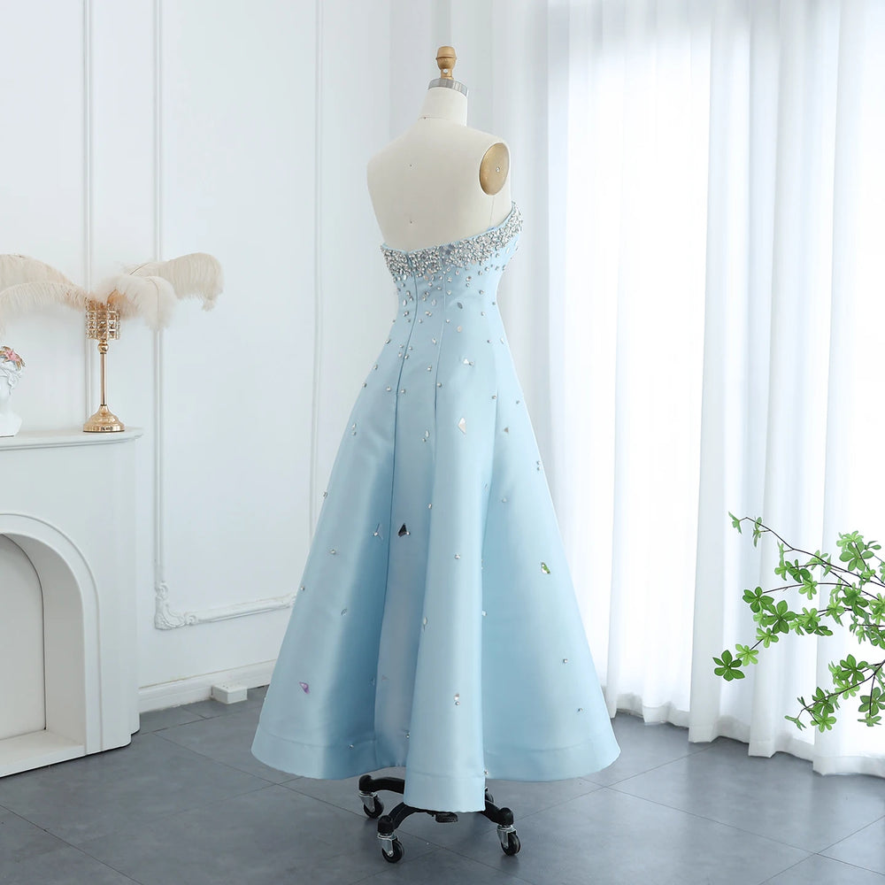 Light blue evening gown on a mannequin in a room with white walls and a plant.