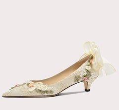 High-heeled shoe with floral design and bow on a light gray background