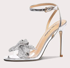 High-heeled sandal with clear strap and decorative bow on a white background