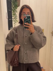 Person wearing a gray cardigan taking a mirror selfie.