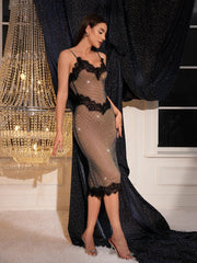 Woman in a sheer dress with black lace details standing in a room with a chandelier.