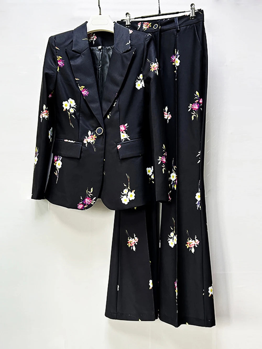 Black floral print blazer and flare pants suit displayed on a hanger.