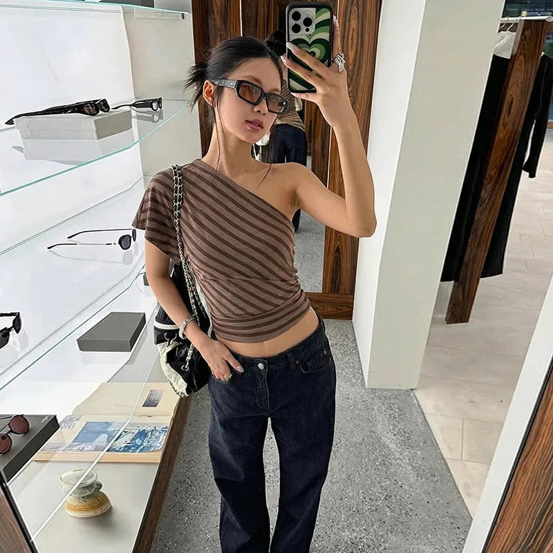 Woman taking a mirror selfie wearing a striped top and jeans in a store.