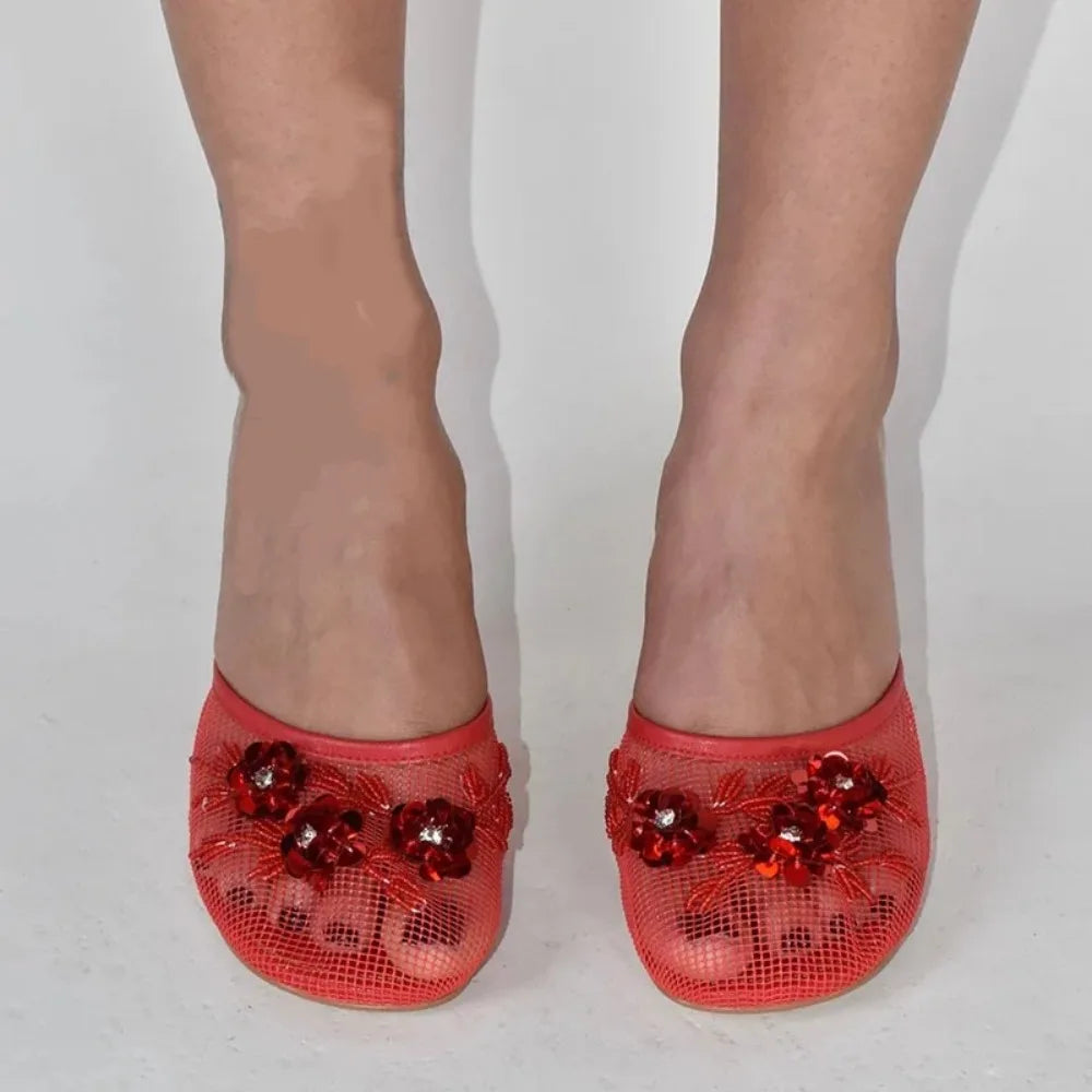 Red mesh wedge mules with floral embellishments on foot