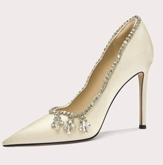 Beige high-heeled shoe with decorative elements on a white background