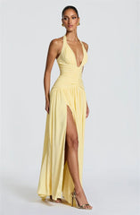 Woman wearing a yellow evening gown with a high slit on a white background