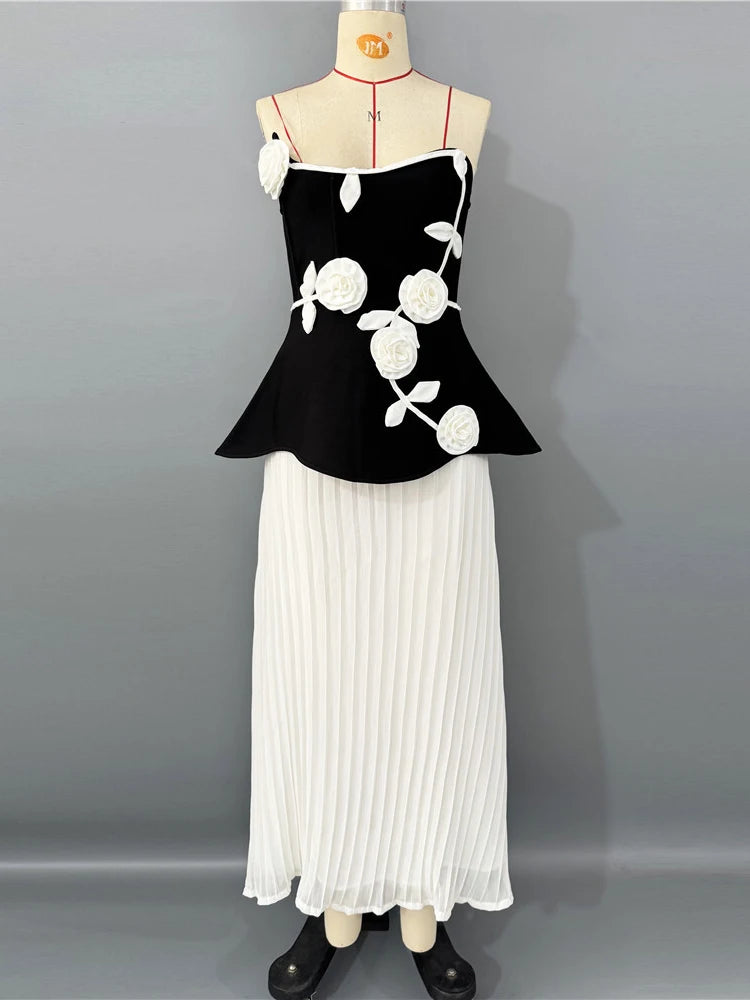 Black top with white floral patterns and a white pleated skirt on a mannequin against a gray background