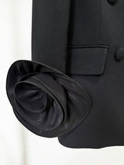 Close-up detail of the floral applique cuff on a black double-breasted blazer.