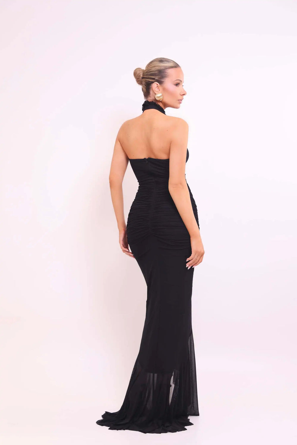 Woman wearing a black halter neck gown on a white background