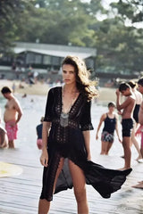 Black midi dress with lace trim and V-neck, worn at the beach.