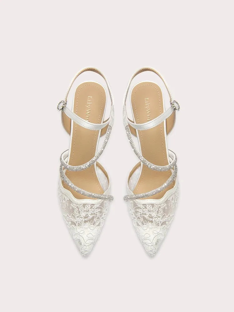 Pair of silver high-heeled shoes with lace detailing on a light gray background