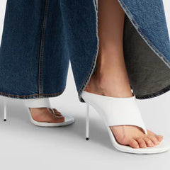 White patent thong heels on a model's feet.