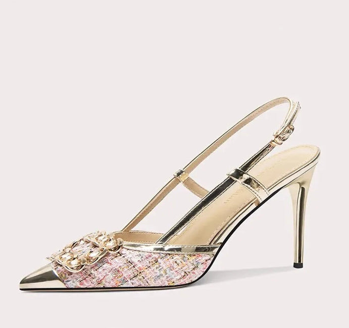 Gold high-heeled shoe with pink glittery sole on a white background