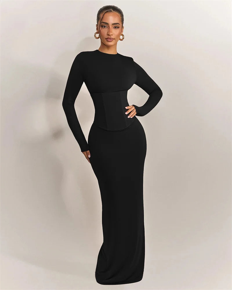 Woman wearing a black long-sleeve gown against a plain background