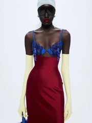 Model wearing a red dress with blue lace details on a white background