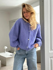 Person wearing a purple cardigan and blue jeans indoors.