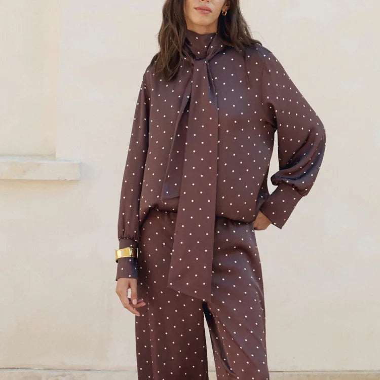 Woman wearing a brown polka dot outfit with a matching scarf against a neutral background