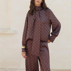 Woman wearing a brown polka dot outfit with a matching scarf against a neutral background