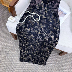Floral-patterned black chair cover draped over a chair with a pearl necklace on top.