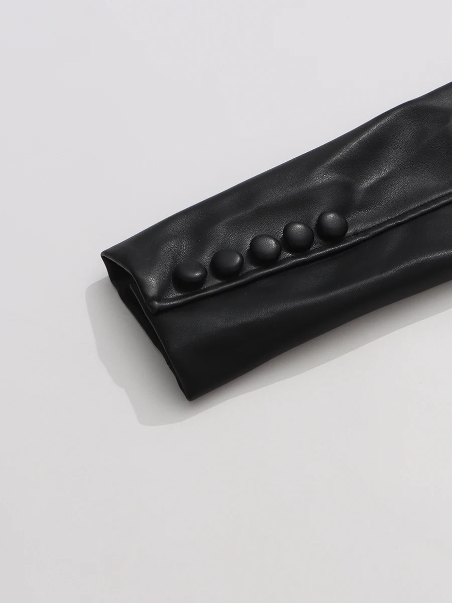 Black leather clutch with button details on a light gray background