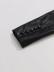 Black leather clutch with button details on a light gray background