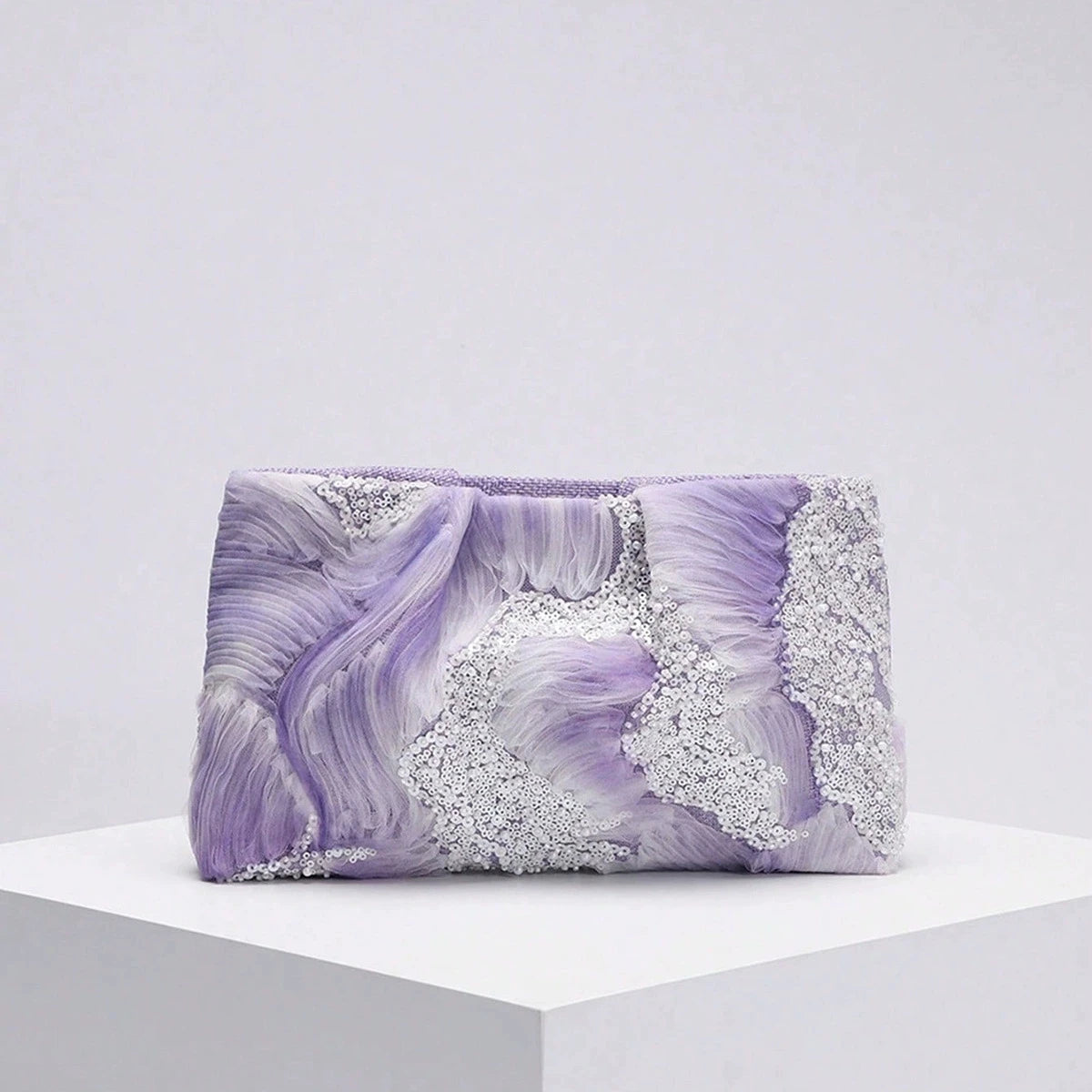 Purple clutch bag with decorative elements on a white platform