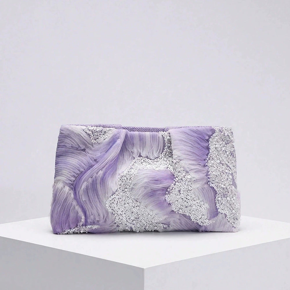 Purple clutch bag with decorative elements on a white platform