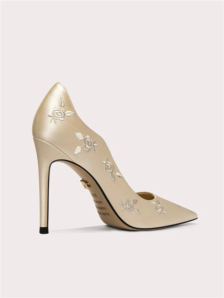 Beige high-heeled shoe with floral embroidery on a light gray background