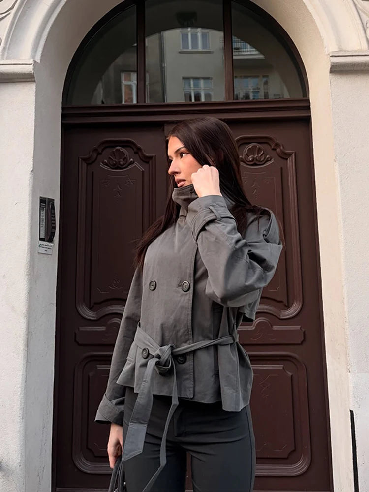Grey belted double-breasted trench coat worn by a woman