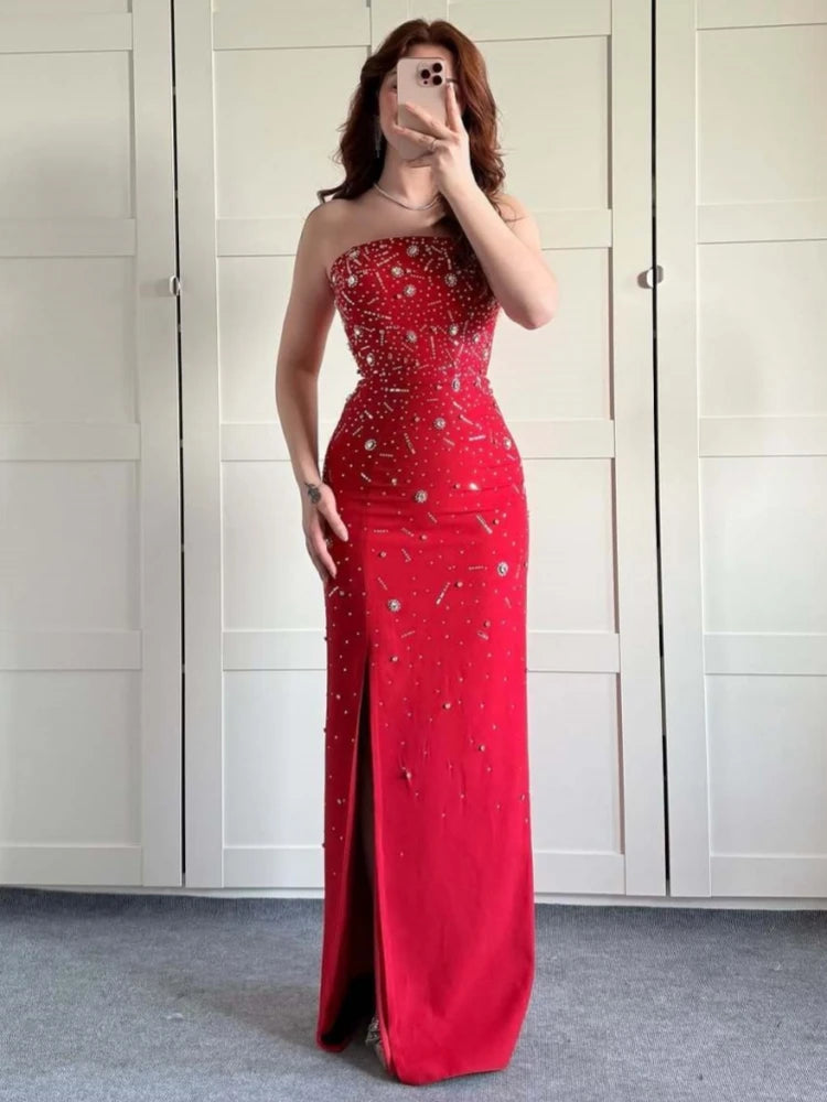 Woman wearing a red strapless evening gown with a slit, standing in front of white closet doors.