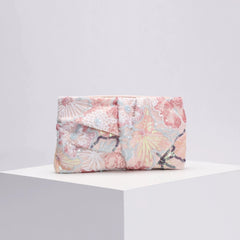 Floral patterned clutch bag on a white surface with a light gray background