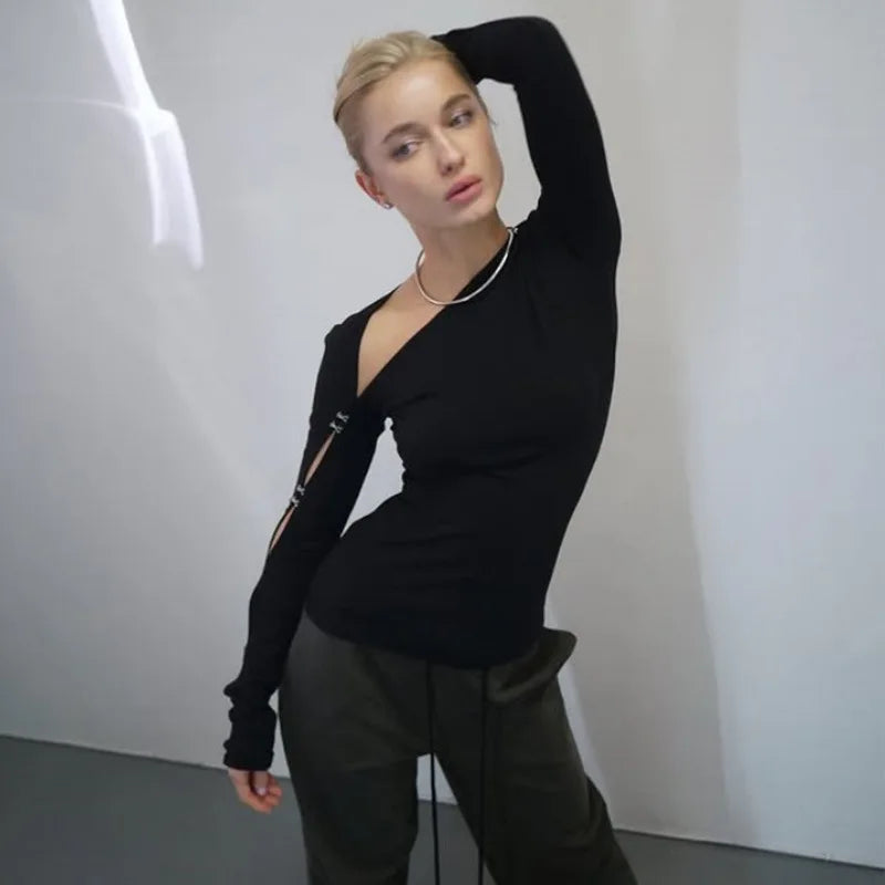 Person wearing a black long-sleeve top and dark pants against a plain background