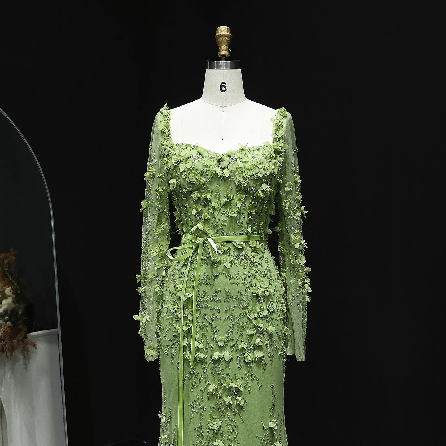 Green floral dress on a mannequin against a black background