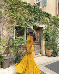 Woman in a yellow dress standing in front of a building with greenery